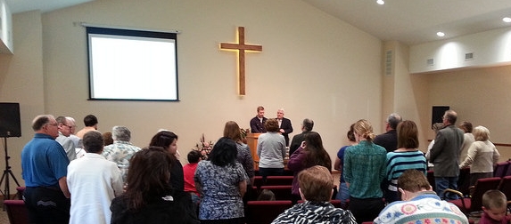 Members standing together at the front of the auditorium during worship